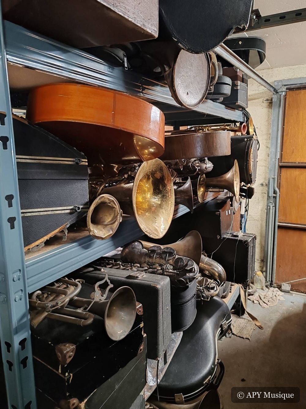 Étagères de l’atelier chargées de cuivres, de saxophones anciens et d’étuis